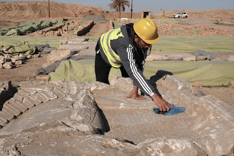 Un experto en arqueología limpia la suciedad de un artefacto en el sitio arqueológico de Nimrud, al sur de Mosul.