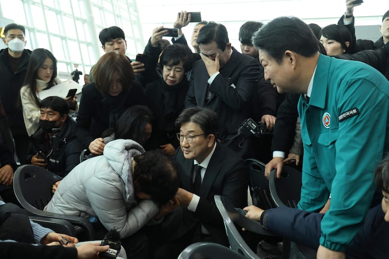 Familiares de los pasajeros del vuelo de Jeju Air son asistidos por las autoridades aeroportuarias. 