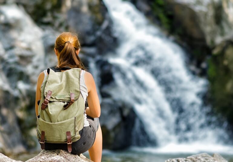 Momento de relax: una joven mira una cascada.