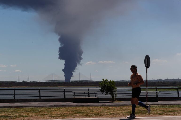 Desde la Costanera de Asunción se observa el humo que se levanta por el incendio en el depósito de cubiertas en Puerto Fénix.