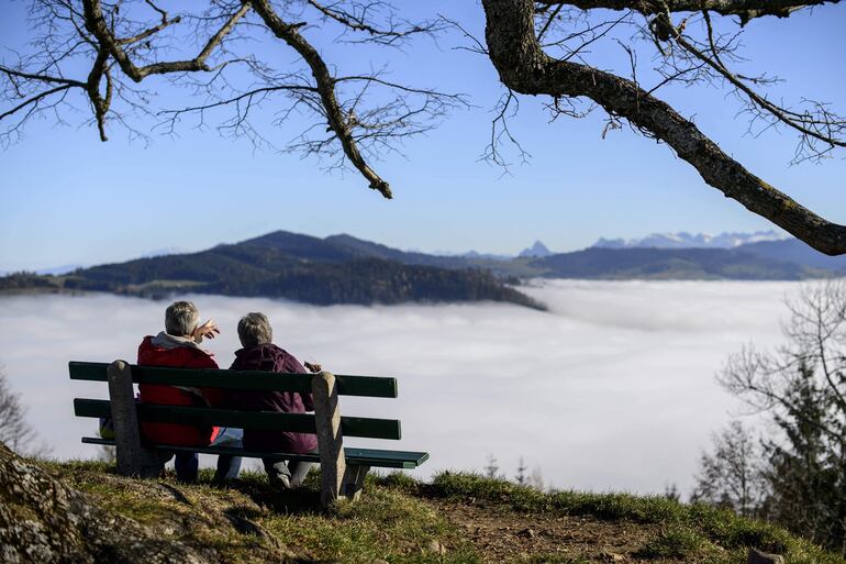 Una pareja de adultos mayores contempla un lago en Suiza. 