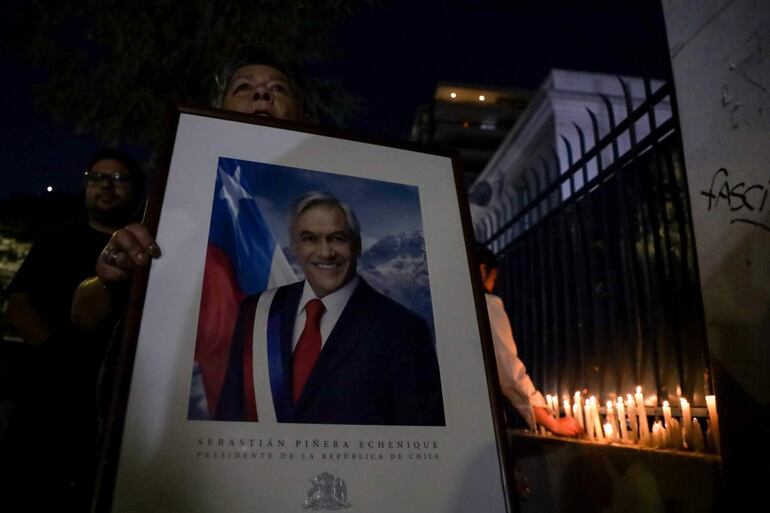 Militantes de Renovacion Nacional encienden velas en la sede del partido en apoyo al expresidente de Chile Sebastían Piñera hoy, en Santiago (Chile). Piñera murió ayer al estrellarse el helicóptero que al parecer pilotaba sobre el Lago Rengo, en el sur del país, informó su oficina. EFE/ Ailen Díaz