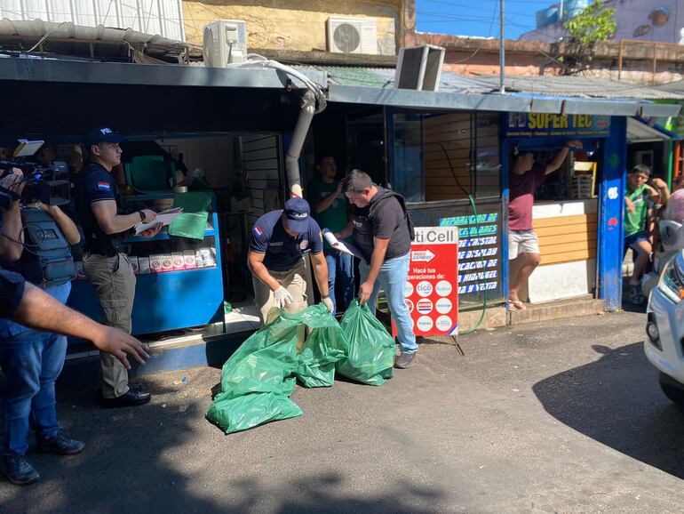 Policías enbolsan los teléfonos celulares que fueron incautados de uno de los locales, ubicados fuera de la Galería San Miguel.