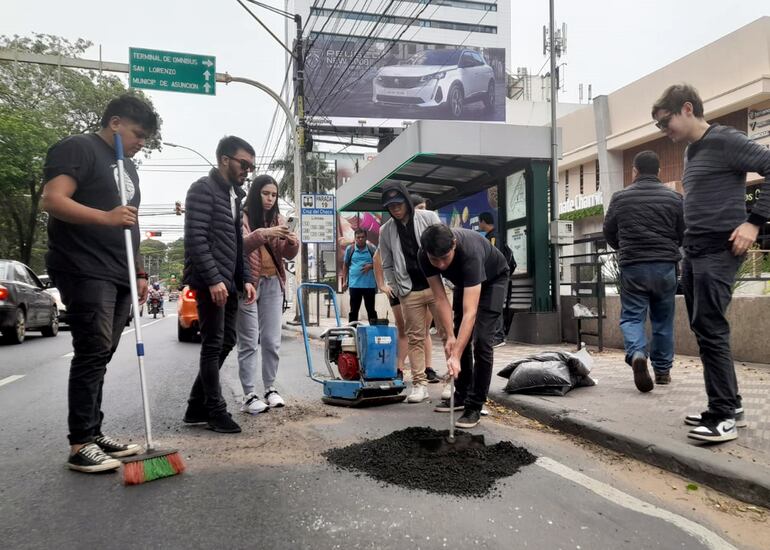 Miembros de la iniciativa Bacheando Py trabajan sobre la avenida Mariscal López, en Asunción, el domingo.