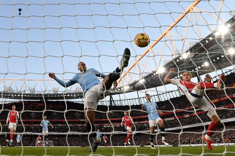 Manchester City's Swiss defender #25 Manuel Akanji (C) and Arsenal's Belgian midfielder #19 Leandro Trossard (R) attempt to get to the ball on the City goal-line, though an offside flag brought the play back, during the English Premier League football match between Arsenal and Manchester City at the Emirates Stadium in London on February 2, 2025. (Photo by Glyn KIRK / AFP) / RESTRICTED TO EDITORIAL USE. No use with unauthorized audio, video, data, fixture lists, club/league logos or 'live' services. Online in-match use limited to 120 images. An additional 40 images may be used in extra time. No video emulation. Social media in-match use limited to 120 images. An additional 40 images may be used in extra time. No use in betting publications, games or single club/league/player publications. / 