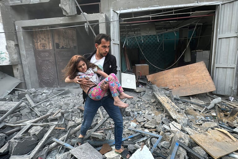 Un hombre lleva en brazos a una niña herida que fue rescatada de un edificio dañado por un bombardeo israelí el pasado jueves en Yabalia, en el norte de la Franja de Gaza.