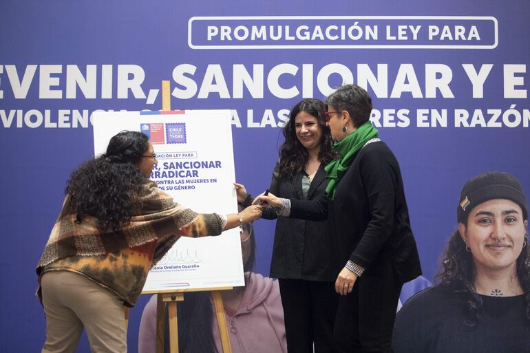 La ministra de la Mujer y la Equidad de Genero, Antonia Orellana (centro), la subsecretaria de la mujer, Luz Vidal Huiriqueo (izquierda), y la senadora, Claudia Pascual, participan en la promulgación de la Ley Integral para prevenir, sancionar y erradicar la violencia de genero, junto a más de 200 mujeres de organizaciones de la sociedad civil, este sábado en el Museo de la Educación Gabriela Mistral en Santiago (Chile). Orellana encabezó este sábado la promulgación de la ley integral contra la violencia hacia las mujeres en razón de su género, iniciativa que se tramitó durante siete años en el Congreso Nacional y que regula mecanismos de prevención, protección, atención, reparación y acceso a la justicia para las víctimas.