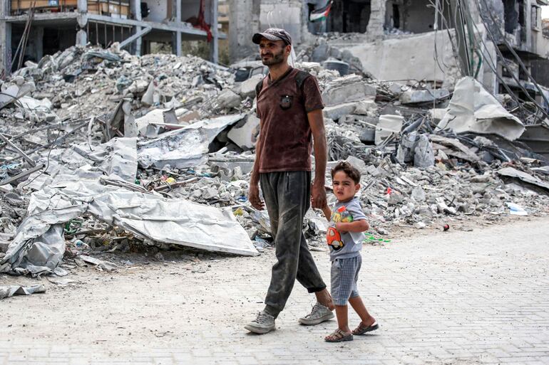 Un hombre y un niño caminan junto a escombros de un edificio colapsado en Jan Yunis, en el sur de la Franja de Gaza.