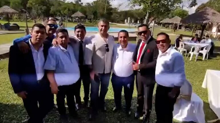  Milner Eustaquio Ruiz, con saco,  corbata y lentes oscuros en el grupo de “amigos”  en un centro recreativo.