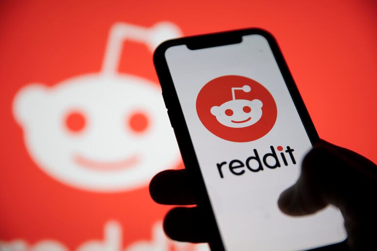 Una persona revisa su celular con el logo de Reddit.