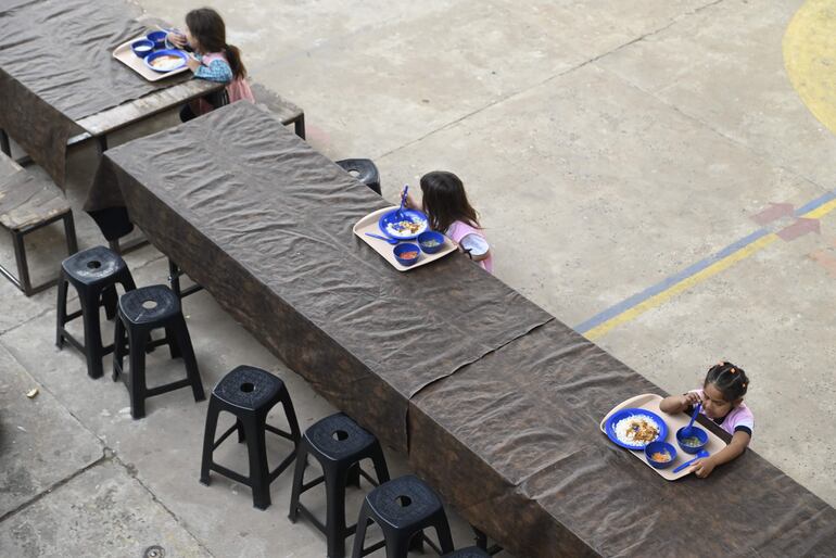 Niños almuerzan en el patio de la escuela Clara Piacentini de Cacace de Asunción, ante la falta de comedores.