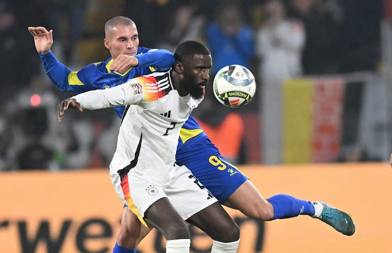 Germany's defender #02 Antonio Ruediger (front) and Bosnia-Herzegovina's forward #09 Luka Kulenovic vie for the ball during the UEFA Nations League football match between Germany and Bosnia and Herzegovina, in Freiburg, on November 16, 2024. (Photo by THOMAS KIENZLE / AFP)