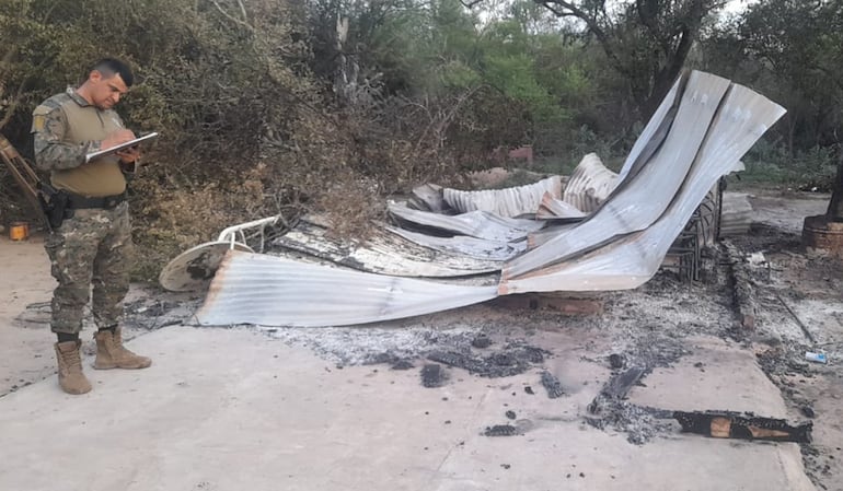 Un policía de Mariscal Estigarribia junto a la precaria vivienda quemada, donde murió la mujer.