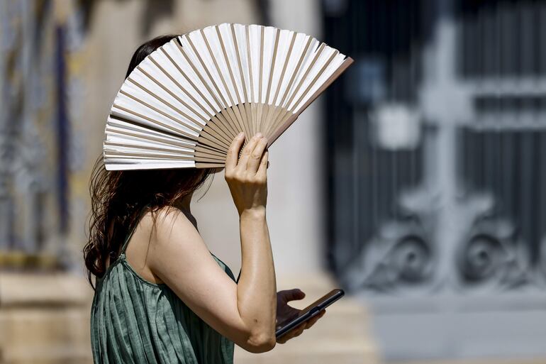 Una mujer se protege del intenso calor con un abanico en las calles de València. 
