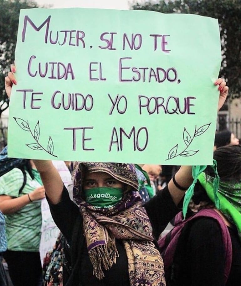 Una mujer sostiene un cartel con una parte de la canción "Te amo", de Lupe.