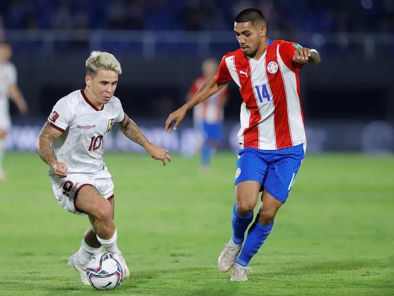 Héctor David Martínez (d), jugador de la selección de Paraguay, enfrenta a Jefferson Soteldo, futbolista de Venezuela, en un partido de Eliminatorias Sudamericanas 2022 en el estadio Defensores del Chaco, en Asunción.