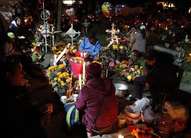 Familiares y amigos visitan a sus fieles difuntos la madrugada del 1 de noviembre de 2024 en el panteón comunal San Gregorio Atlapulco, en la Ciudad de México (EFE).
