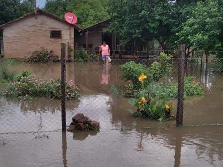 Mujer camina en el agua. La lluvia inundó su casa e inutilizó varias de sus pertenencias.