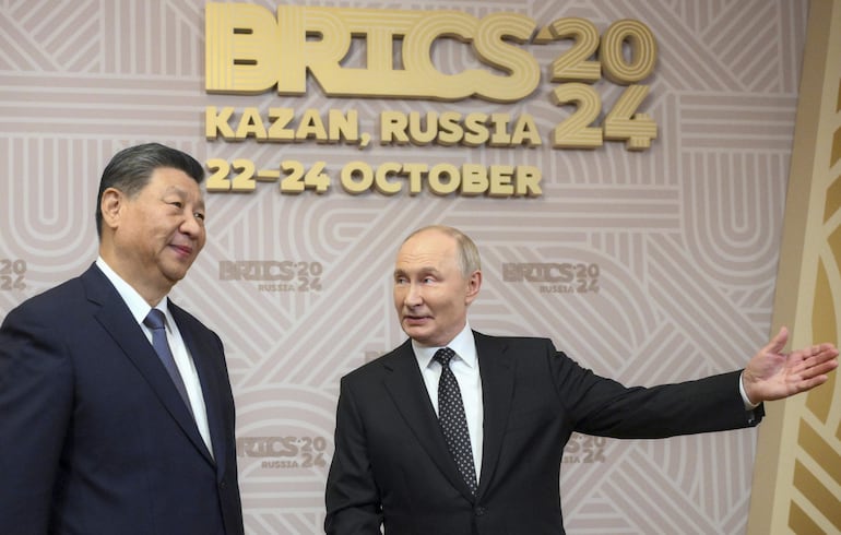 El presidente ruso Vladimir Putin (d) saluda al mandatario chino Xi Jinping.