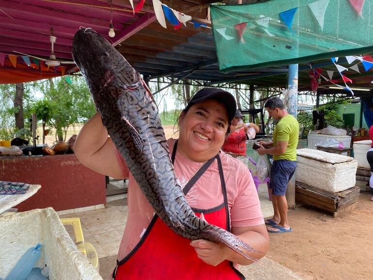 Gladys Gómez, vendedora de pescado atajando un ejemplar de surubí.