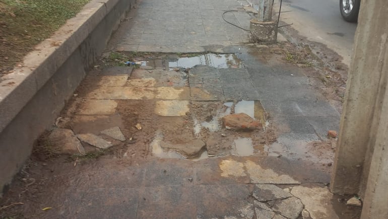 Vereda destrozada y con agua en Asunción.