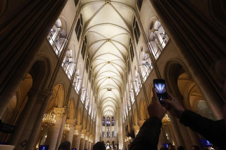 La gente toma fotografías adentro de la catedral de Notre Dame.