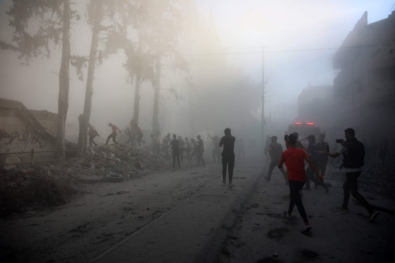 Varias personas corren hacia el sitio de un ataque aéreo israelí, el domingo en la Ciudad de Gaza.
