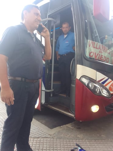 Anibal Guerrero, hablando por teléfono y el conductor Isidro Barrios, en la puerta del ómnibus de la Guaireña.