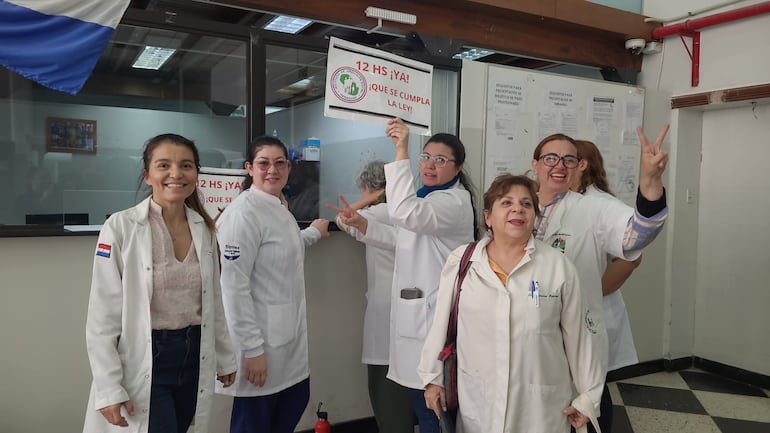 Médicos del IPS levantan carteles para exigir el cumplimiento de la Ley 7.137 que establece la carga horaria laboral a 12 horas semanales. 