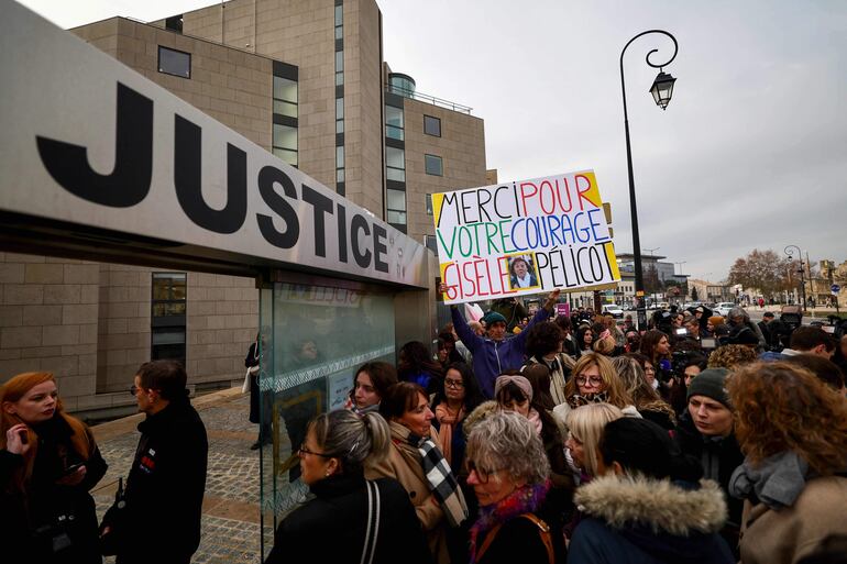 El artista y activista francés Voltuan sostiene un cartel que dice en francés "Gracias por tu valentía, Gisele Pelicot", mientras la gente se reúne frente al tribunal de Aviñón el 19 de diciembre de 2024, esperando el veredicto en el juicio de un hombre, junto con otras 50 personas, acusado de drogar a su esposa y orquestar múltiples violaciones durante casi una década.