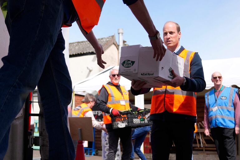 William también cargó varias cajas a los vehículos que trasladan la comida solidaria. (Alastair Grant / POOL / AFP)