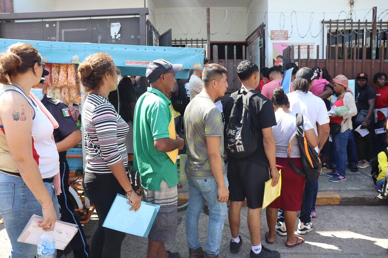 Migrantes hacen fila frente a las instalaciones de la Comisión Mexicana de Ayuda a Refugiados (Comar) este viernes, en Tapachula (México).