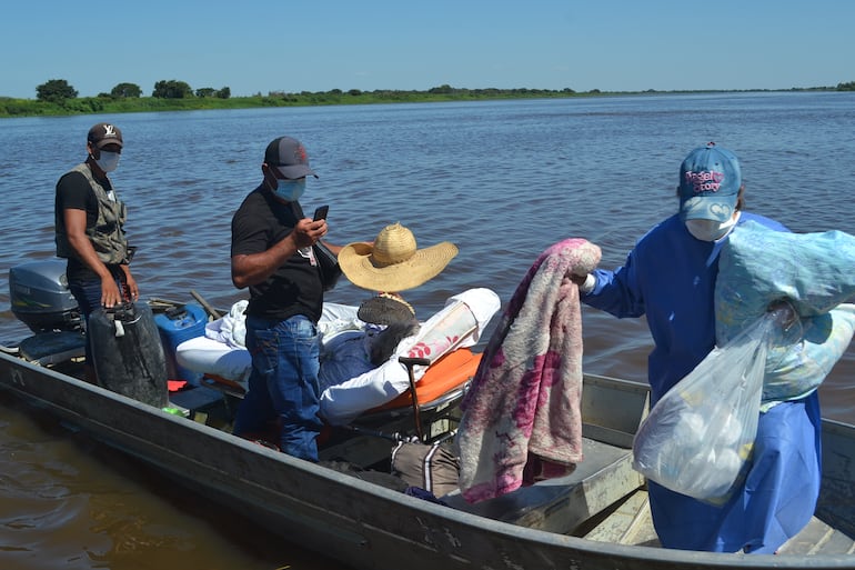 Funcionarios de salud y familiares se disponen para el traslado por el río Paraguay de un paciente del Hospital Regional de Fuerte Olimpo donde principalmente faltan médicos especialistas,  unidad de cuidados intensivos, equipamiento de laboratorios de diagnóstico, entre otros. Cientos de kilómetros deben navegar en la pequeña e incómoda embarcación. 