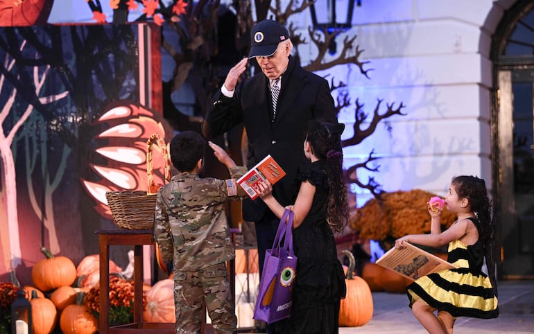 El presidente de Estados Unidos Joe Biden entrega caramelos a dos niños disfrazados durante la celebración de Halloween en la Casa Blanca en Washington. 