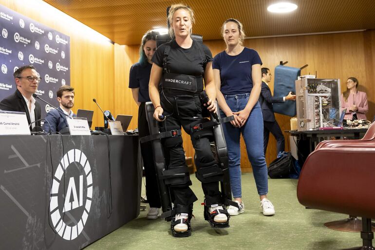 Charlotte Faibank, centro, piloto de la empresa "Wandercraft" camina con un exoesqueleto andante autónomo, que permite a las personas parapléjicas volver a caminar durante la exhibición de exoesqueletos controlados mentalmente y otras interfaces cerebro-máquina impulsadas por IA Tecnología. 