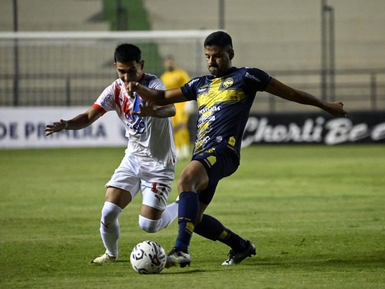 Gabriel Aguayo (i), futbolista de Cerro Porteño, pelea el balón con César Benítez, jugador del Sportivo Trinidense, en un partido del torneo Apertura 2024 del fútbol paraguayo en el estadio Arsenio Erico, en Asunción, Paraguay.