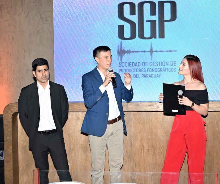 Walter Riveros, tesorero de SGP; Jorge Aguilera, presidente de SGP y Kassandra Frutos, presentadora del acto.