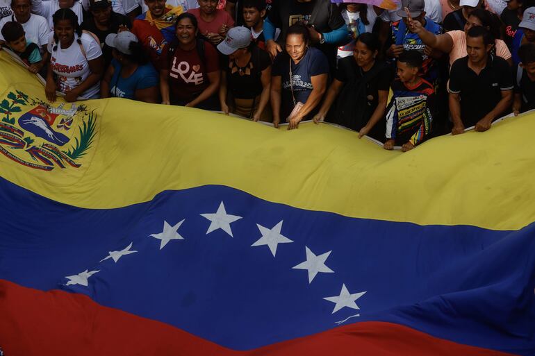 Seguidores del presidente de venezuelano Nicolás Maduro sostiene una bandera de Venezuela este jueves, en Caracas (Venezuela).