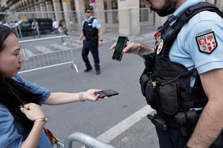 Un gendarme francés cheque el código QR de acceso de una ciudada en una zona controlada por los Juegos Olímpicos. 