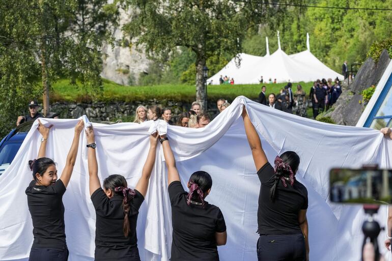 Staff de  la boda cubre el paso de la novia con sábanas blancas de los papparazzis.
