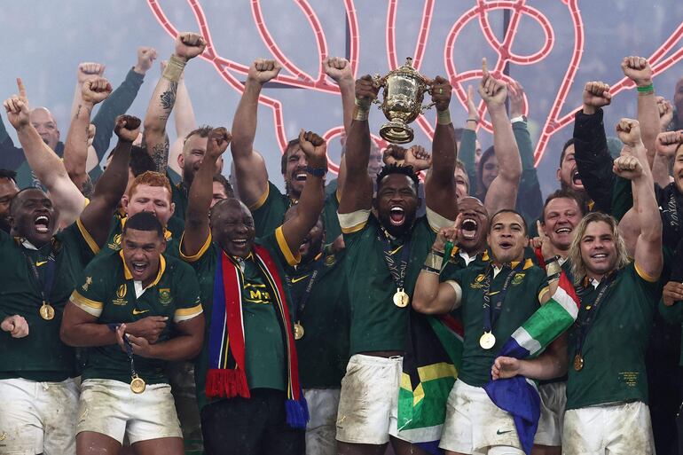 El capitán  Siya Kolisi (C) celebra con la copa del mundo, flanqueado por el presidente Cyril Ramaphosa. AFP