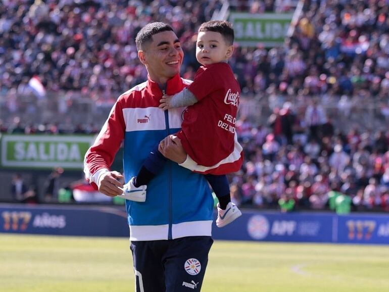 Miguel Almirón, ingresando al campo de juego del Defensores del Chaco con Francesco en sus brazos, en la previa del partido amistoso de la selección paraguaya contra Nicaragua en el Día del Padre.