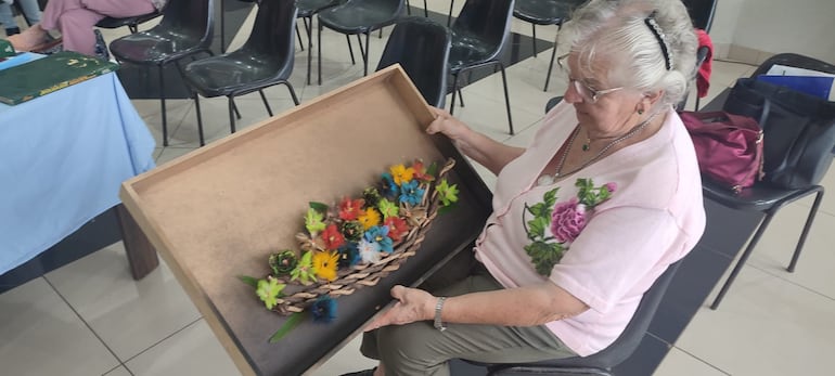 Doña Elena de Soloaga muestra una de sus más recientes obras. Algunos trabajos le llevan hasta dos años de tiempo, buscando plumas y elaborando la obra.