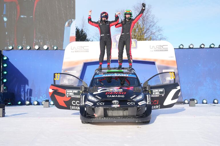 Elfyn Evans y Scott Martin celebran el triunfo en el rally blanco arriba del techo del rendidor Toyota GR Yaris Rally1.