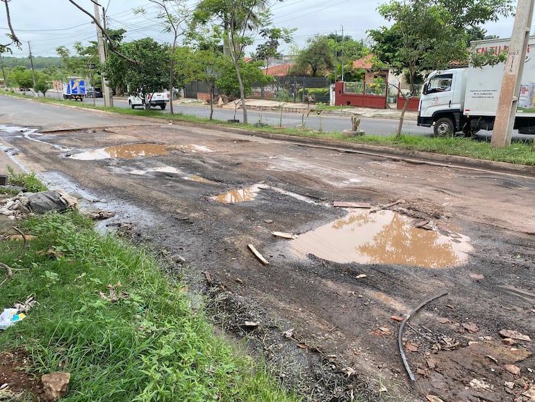 La avenida General José Eduvigis Díaz, en Mariano Roque Alonso, con baches profundos llenos de agua tras las lluvias, restos de escombros y una capa asfáltica visiblemente deteriorada, dificultando el tránsito vehicular.