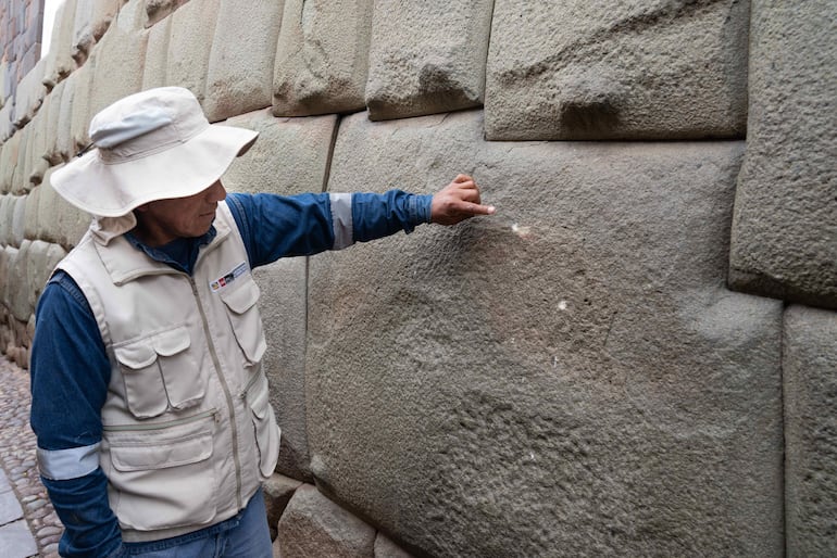 Un funcionario del Ministerio de Cultura de Perú observa daños en la 'piedra de los 12 ángulos' este martes, en el Cuzco (Perú).