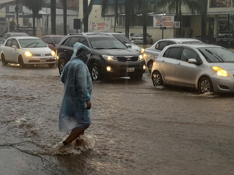 Peatón cruzando la avenida Eusebio Ayala, en medio del raudal.