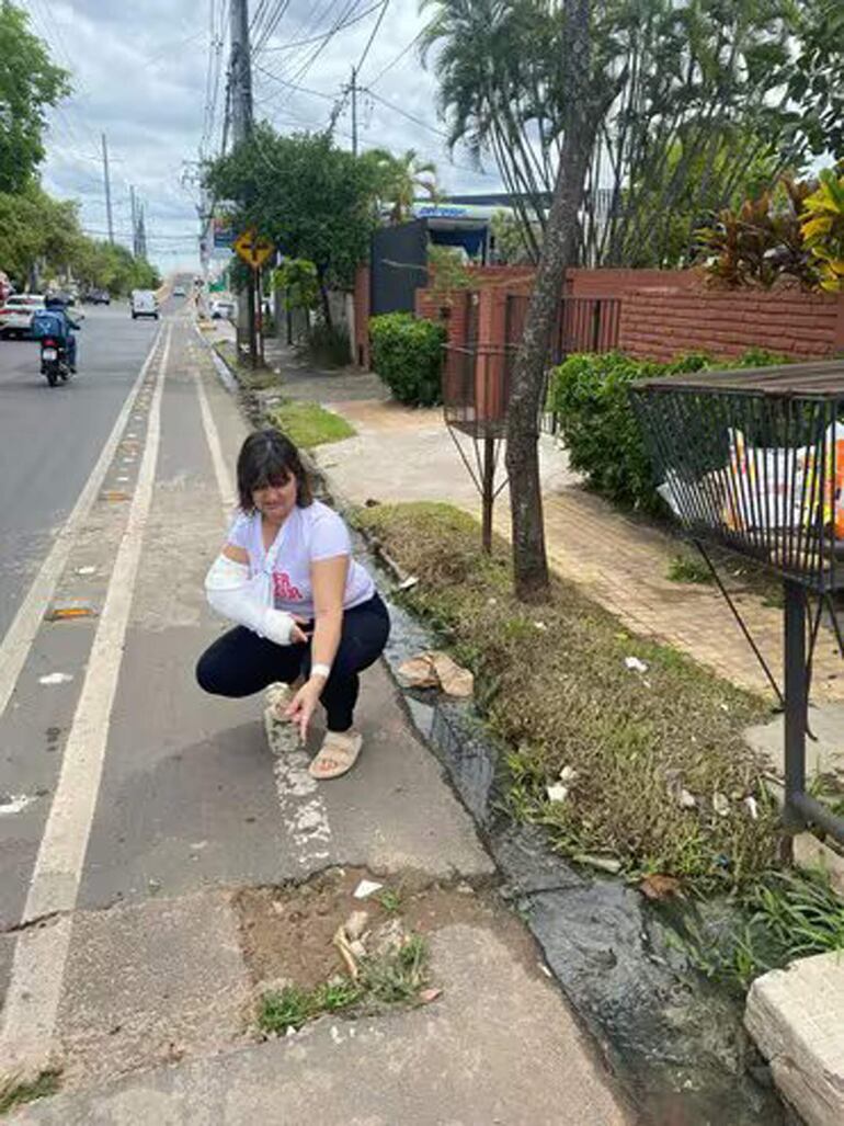 La ciclista, gravemente afectada en su brazo, muestra el bache por el cual cayó. 