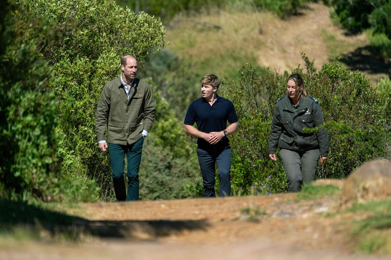 El príncipe de Gales camina con la directora del Parque Nacional Table Mountain, Megan Taplin, y el conservacionista australiano y embajador mundial del Premio Earthshot, Robert Irwin, durante su visita a Signal Hill en Ciudad del Cabo. (Jerome Delay / POOL / AFP)