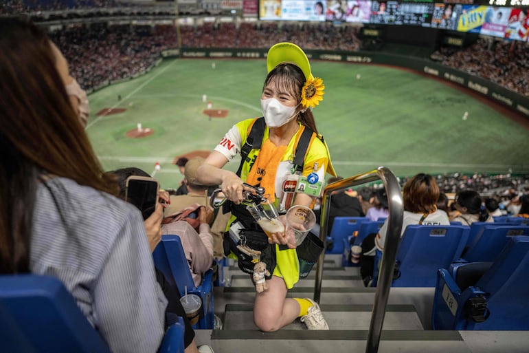 Recorren las gradas con sus surtidores de cerveza a la espalda: en Japón, esas vendedoras ambulantes en los estadios de béisbol representan una tradición aún muy popular, aunque sus condiciones de trabajo pueden despertar algunos interrogantes.